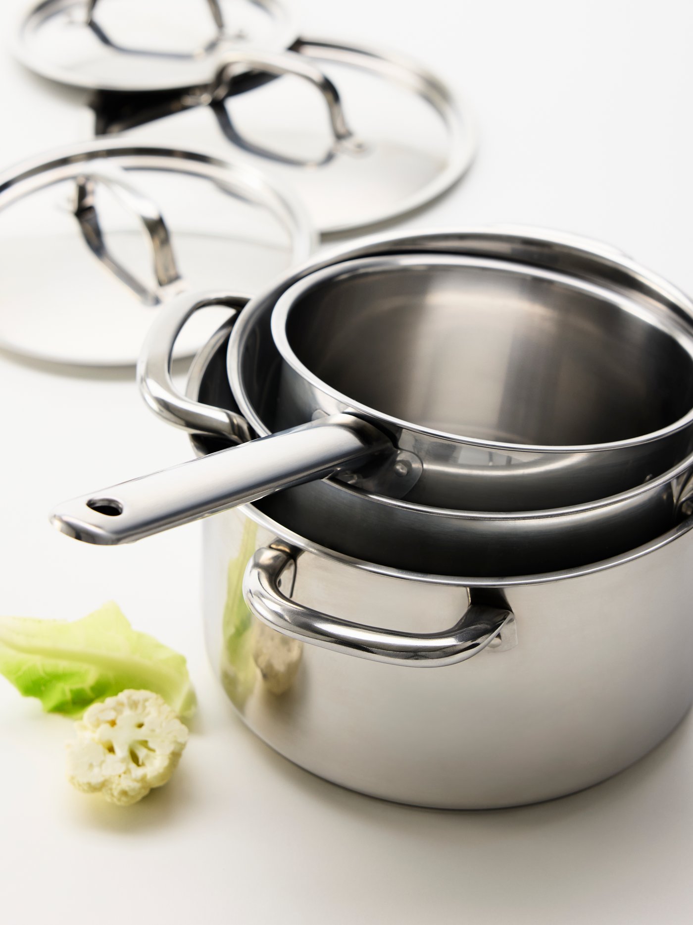 Close-up three of stacked IKEA 365+ stainless steel pots, with the lids in the background.