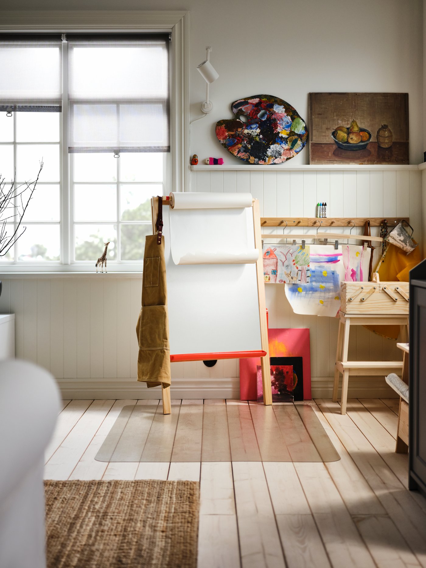 Estudio de arte con un taburete, un organizador de escritorio, cuadros y un caballete de pino macizo plegable con una pizarra blanca y un rollo de papel.