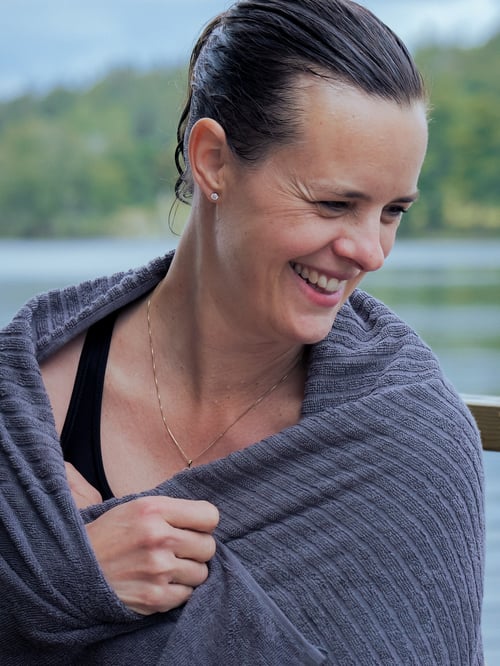 Outdoor featuring a happy person covered with a dark grey terry VÅGSJÖN bath towel fully made of cotton.