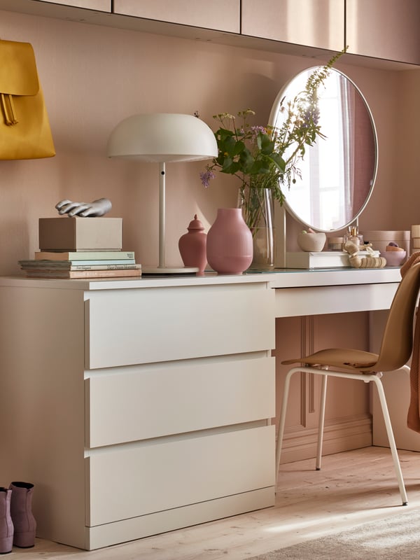 A pink shelf behind a bright desk.
