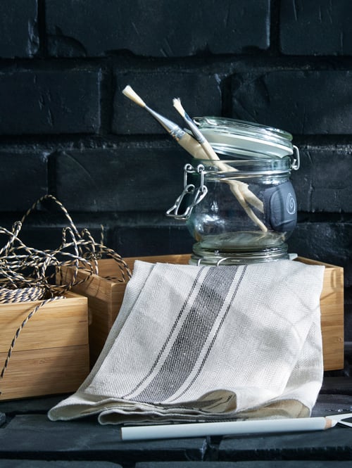 A set of three, bamboo DRAGAN boxes with a tea towel, striped twine and a glass jar that's open with paintbrushes inside.