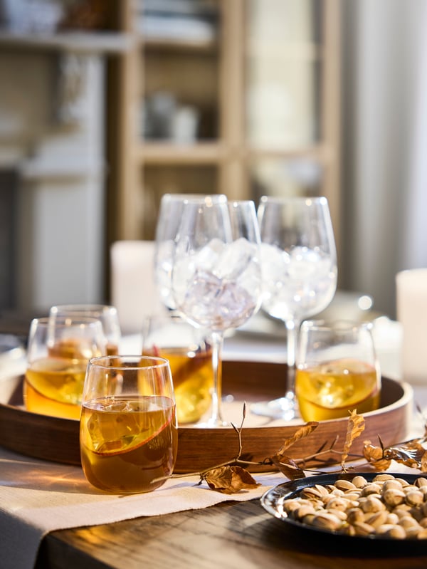 Large round wooden tray filled with different glassware and some filled with liquid.