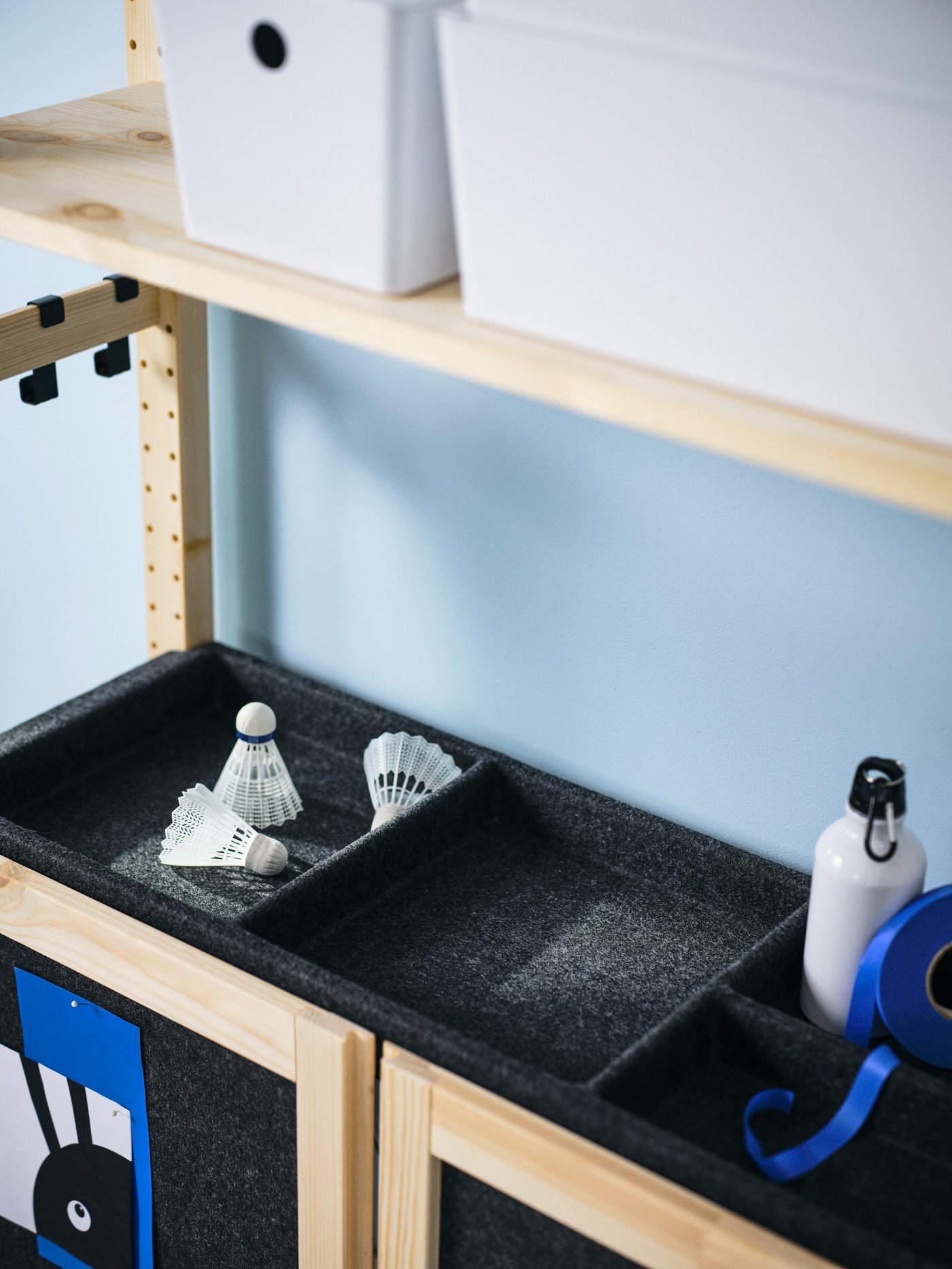 IVAR shelf in dark grey felt material showing several shuttlecocks and sports equipment being organised on top. 