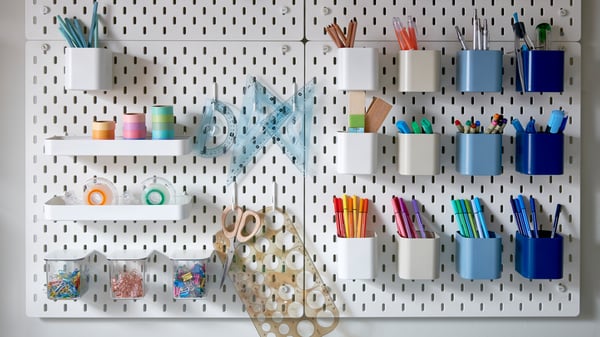 A SKÅDIS pegboard with hanging organizers, with art supplies in them.