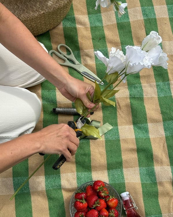 En person klipper till blommor till en midsommarkrans.
