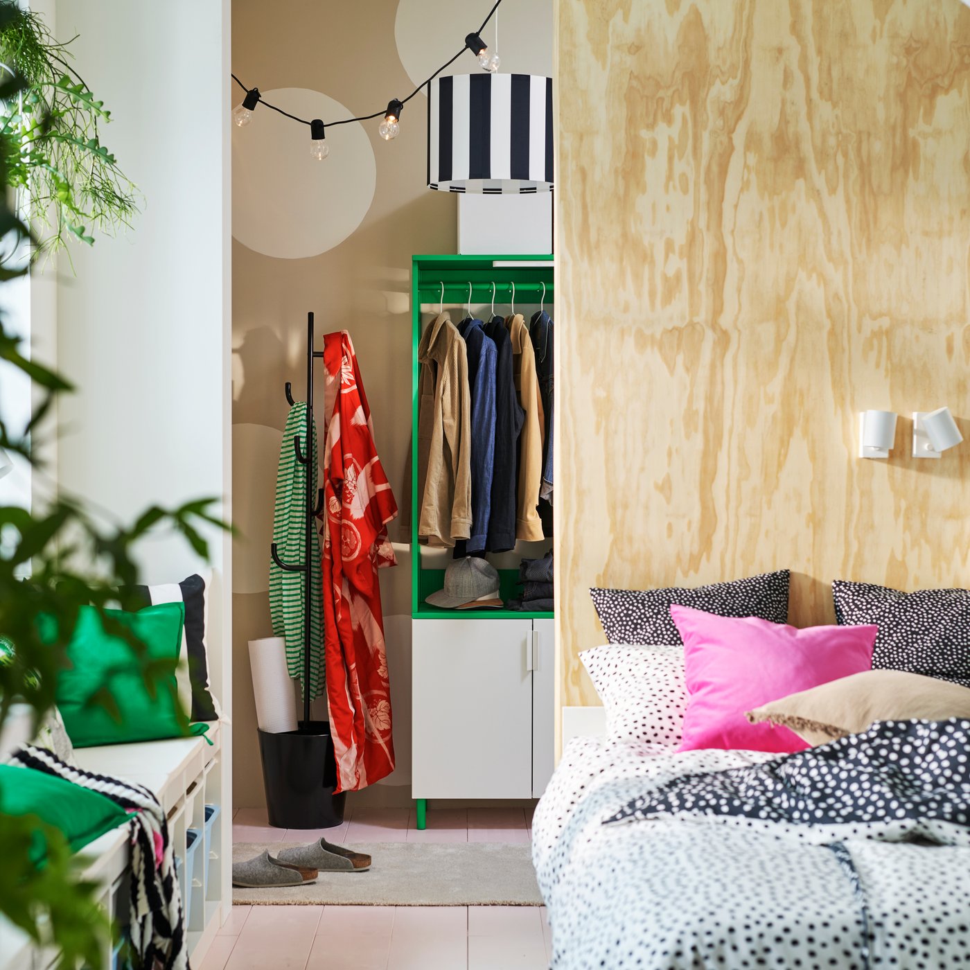 A VIHALS bed in front of a room divider that has a white/green PLATSA wardrobe with 4 doors and a coat rack behind it.