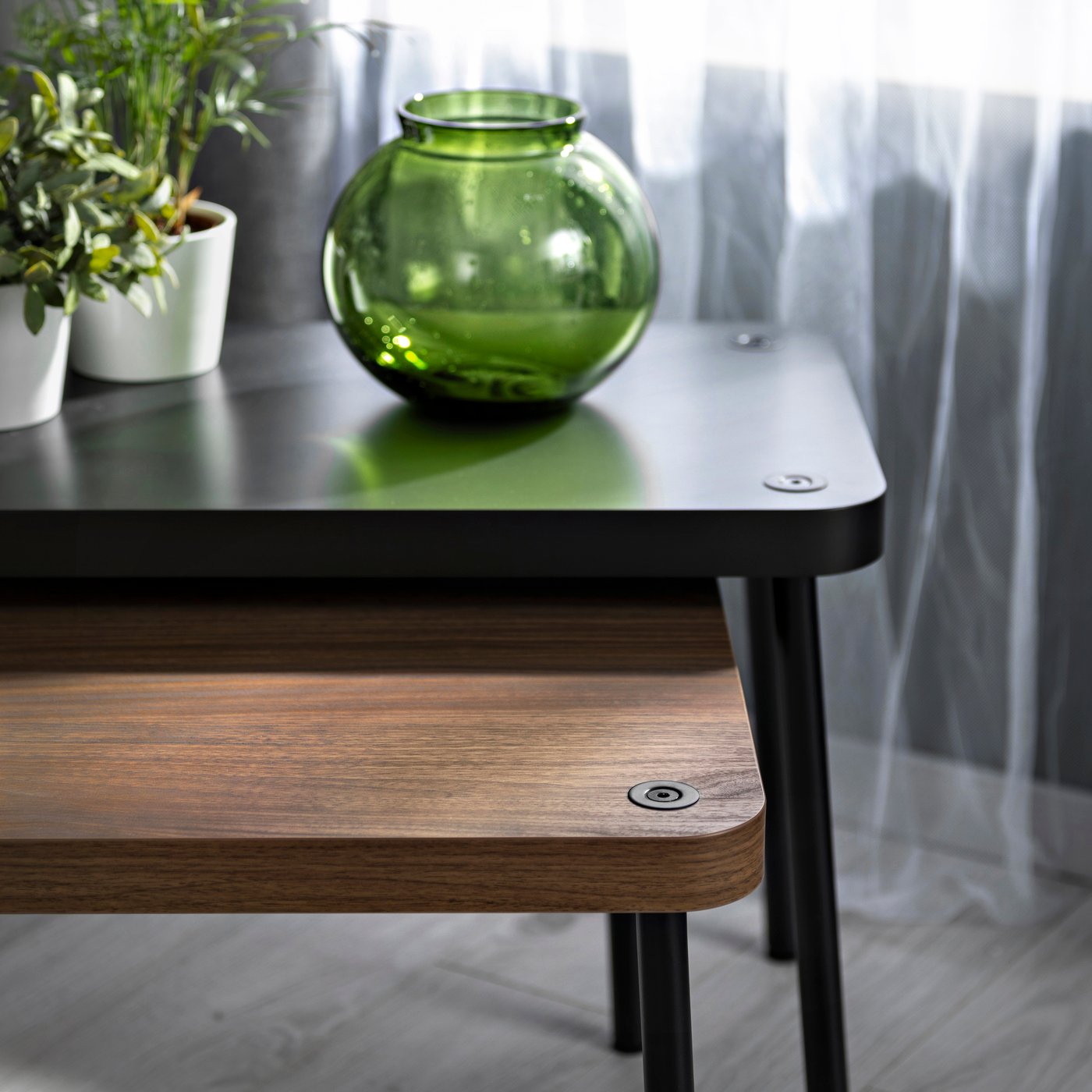 Svart satsbord med två bordsskivor och en grön glasvas som dekoration.