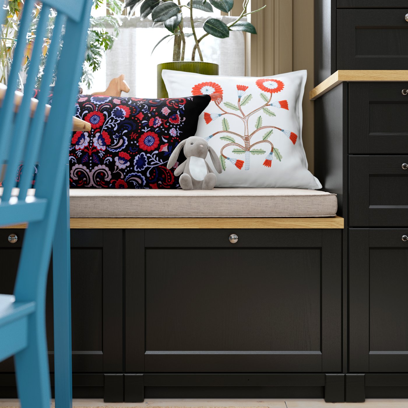 A sitting bench featuring a black stained LERHYTTAN drawer front adjacent to decorative cushions and plants.