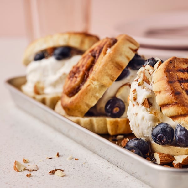 Tri KAFFEREP pogačice puž s cimetom pečene na žaru, sladoled, borovnice, javorov sirup i seckani bademi na metalnoj tacni za serviranje.