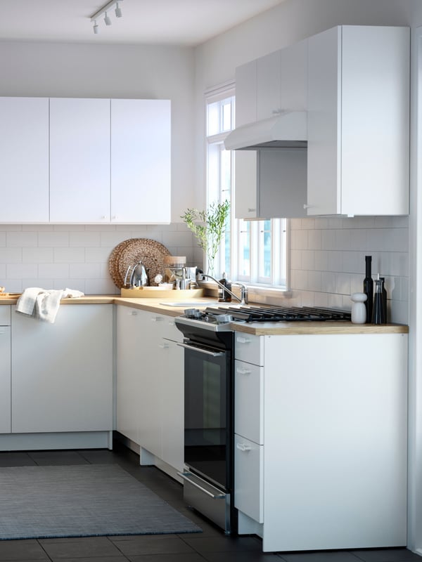 Una cocina con muebles KNOXHULT blancos y cubierta de cocina de madera.