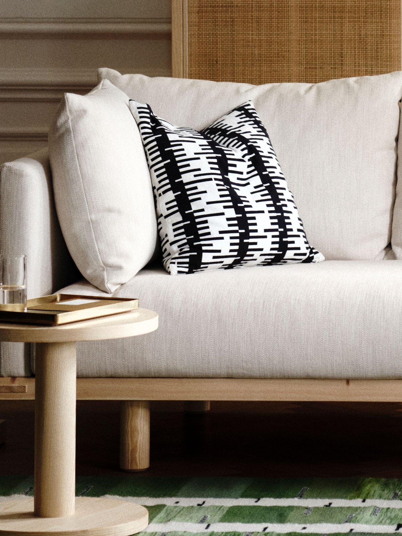 An off-white/black STOCKHOLM 2025 cushion cover in the living room