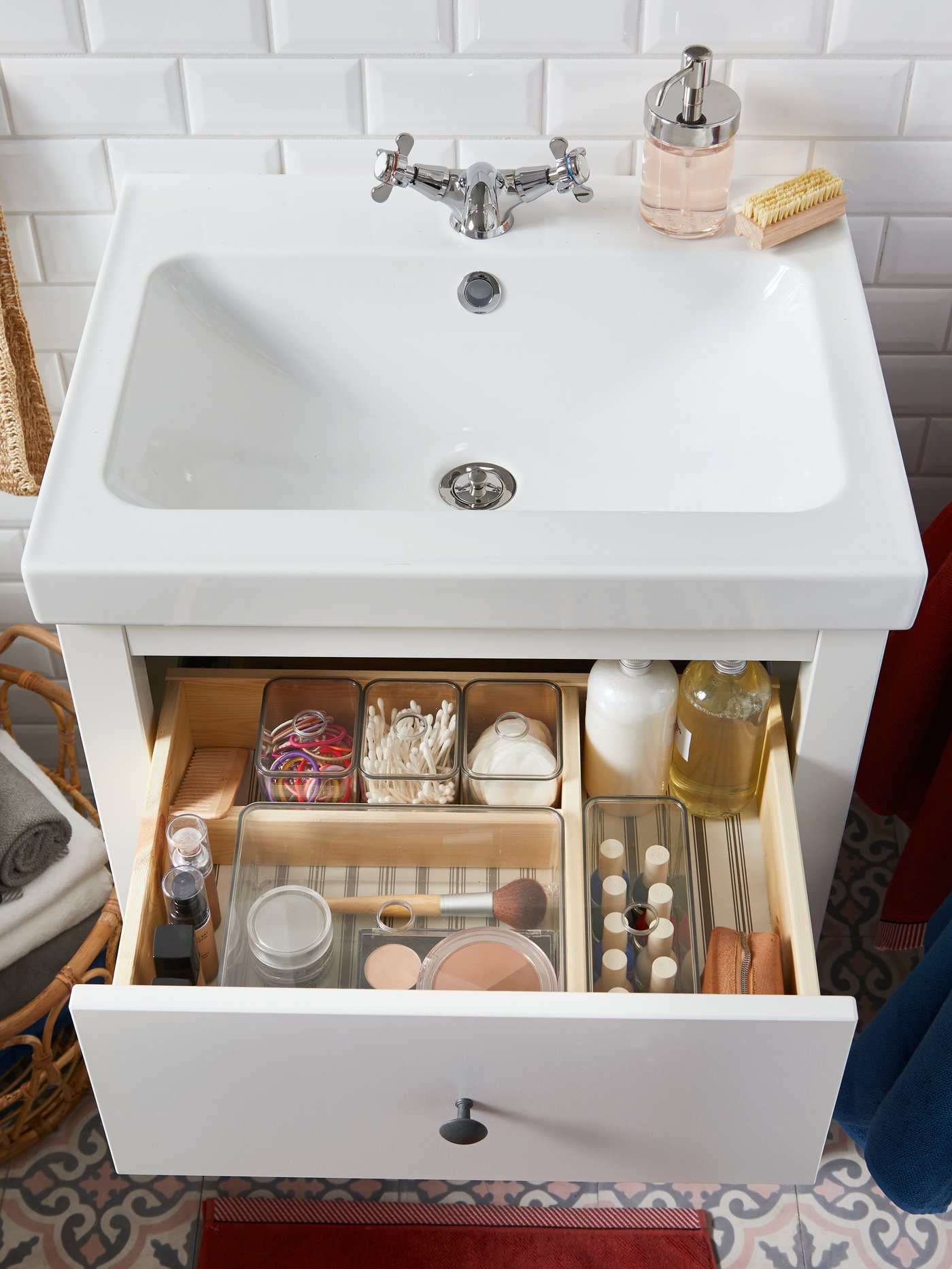 Sink berwarna putih dengan laci terbuka yang mengandungi kotak GODMORGON gelap yang mengandungi produk dan aksesori kecantikan.