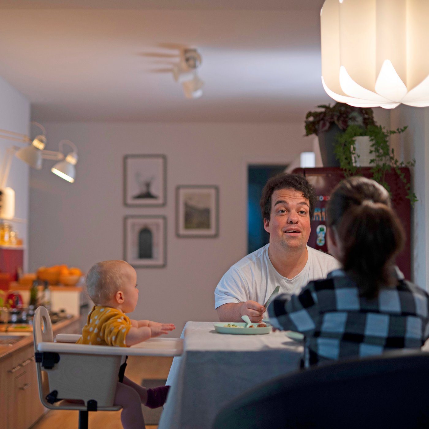 A man, a woman, and a toddler sit at a kitchen table.