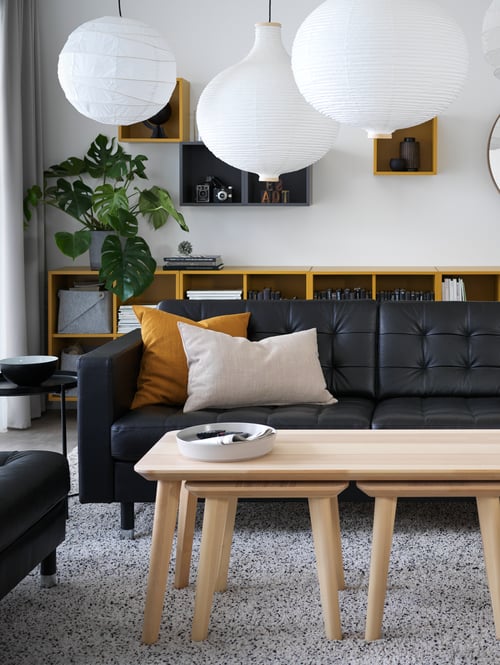 A living room has ash veneer nesting coffee tables in front of a LANDSKRONA three-seat sofa in Grann/Bomstad black/metal.