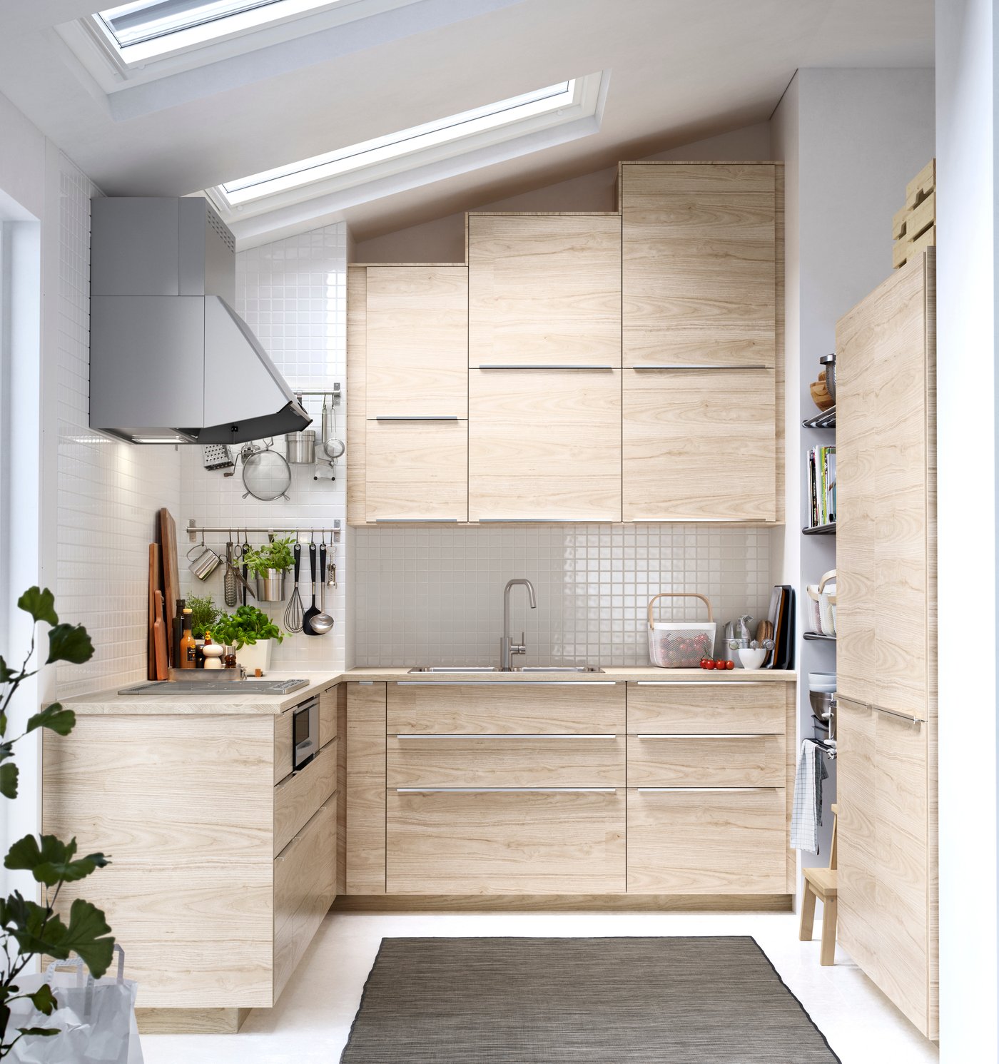 Imagen frontal de una cocina METOD con puertas y frentes de cajón color madera clara, en una cocina con cielo en pendiente e iluminada a través de dos tragaluces. 