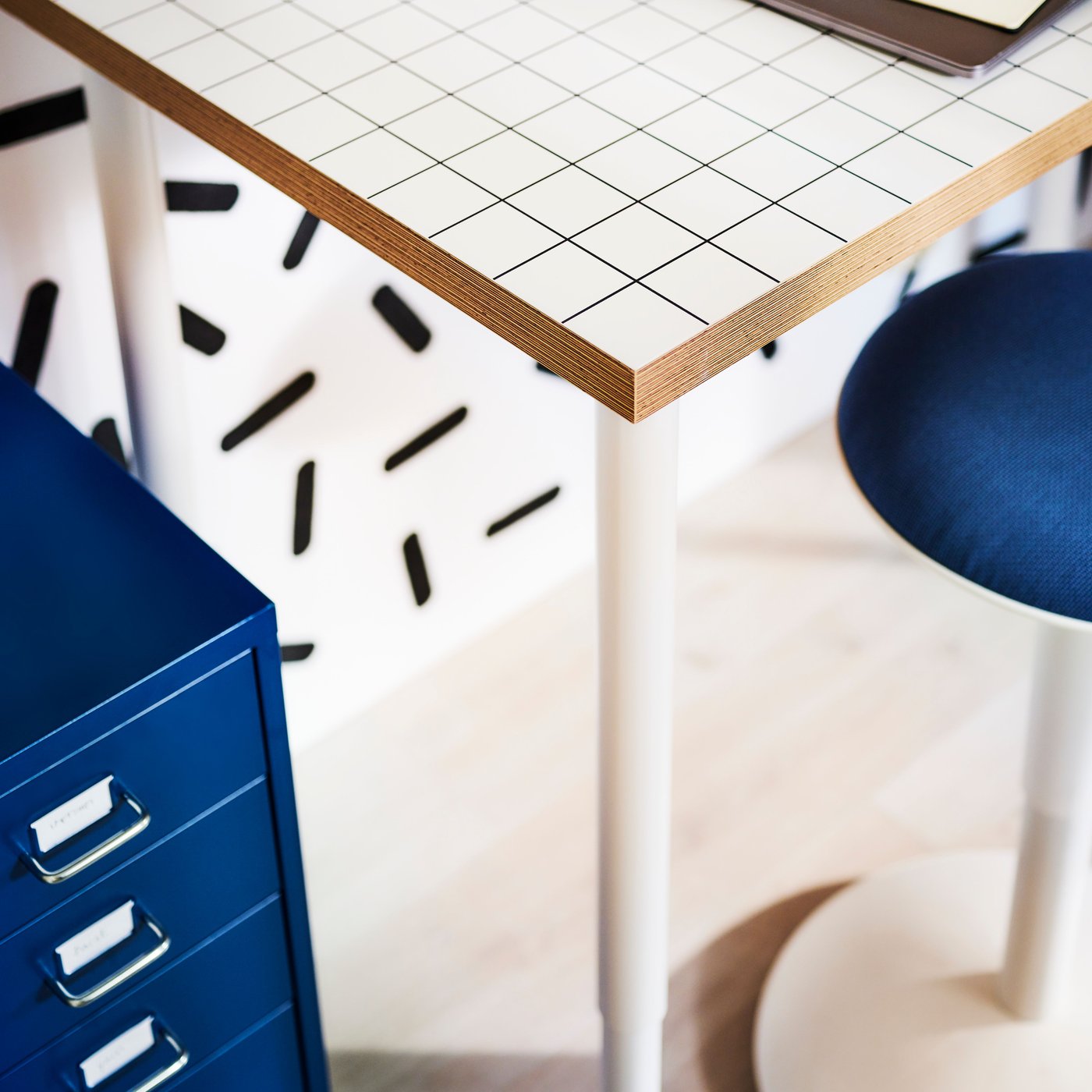 A colourful space with a workspace formed by a graphic-pattern LAGKAPTEN tabletop, OLOV legs and a NILSERIK standing support.
