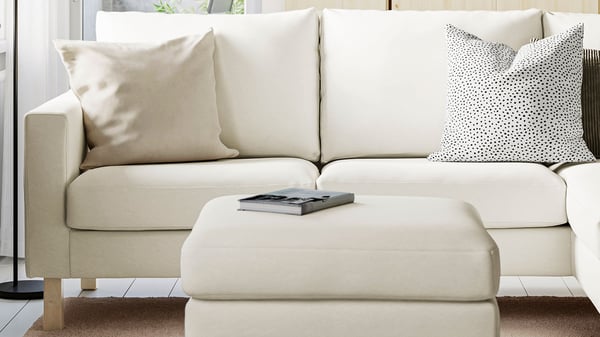 Ljus SALTSJÖBADEN soffa med matchande fotpall i en stilren och ljus vardagsrumsmiljö.


