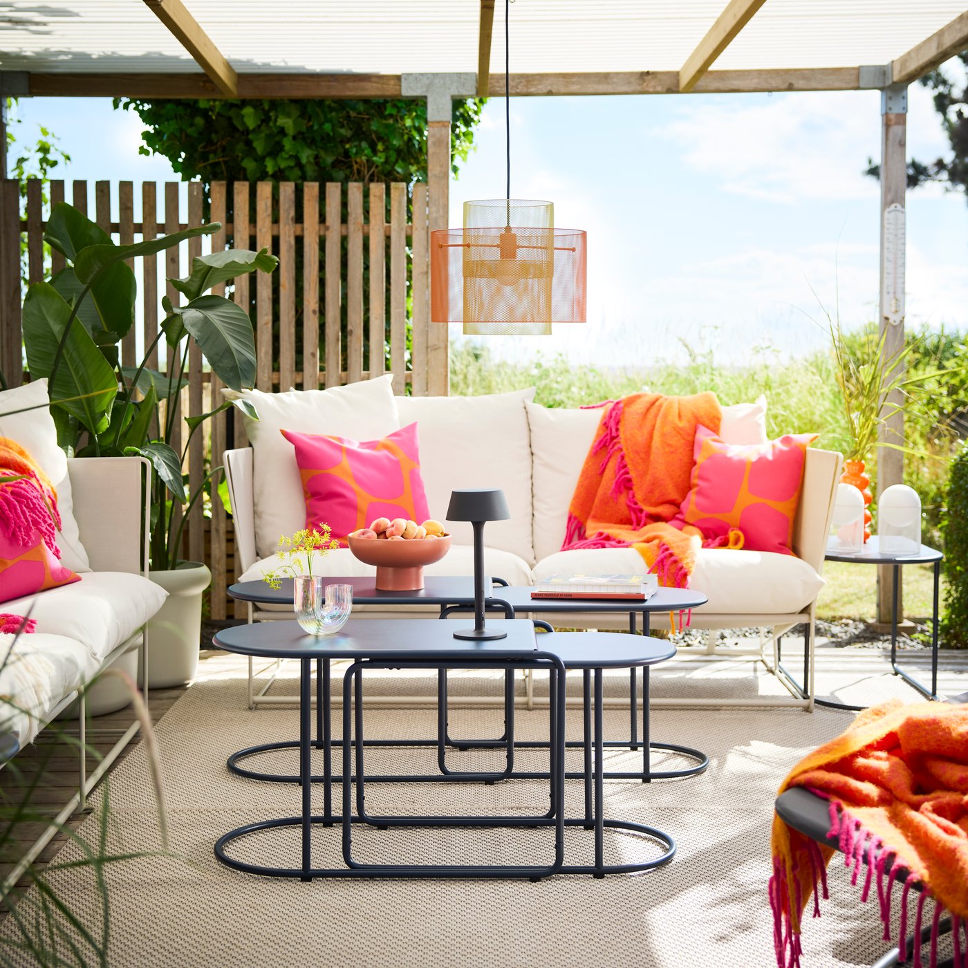 Een loungehoek buiten onder een dakterras met zwartblauwe GRYTSHOLM-tafels met fruit en decoraties. 