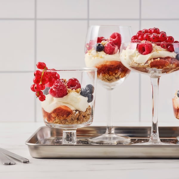 Des verres de formes différentes remplis de cheesecake aux biscuits à l’avoine et à la confiture de framboises sont posés sur un plateau métallique.