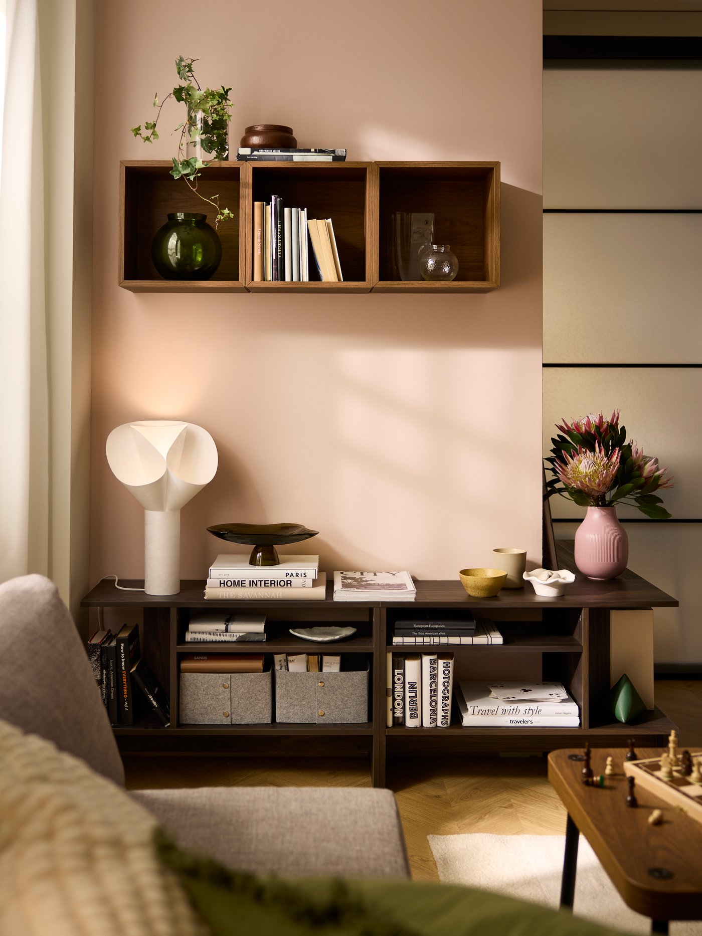 A sunlit living room with a row of EKET cube cabinets on the wall above side-by-side, display-storage HOLMERUD side tables.