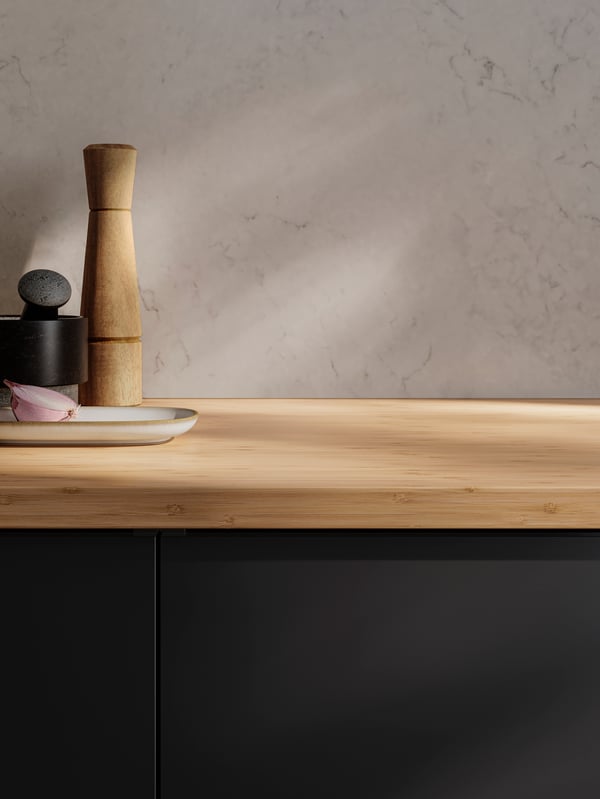 A kitchen with NICKEBO fronts in matt anthracite, a splashback with marble effect and a HOLMARED worktop in bamboo/veneer.