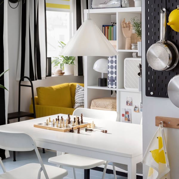 A VIHALS extendable table and VIHALS folding chairs stand in a small dining room area under a white ZEBRASÄV pendant lamp.