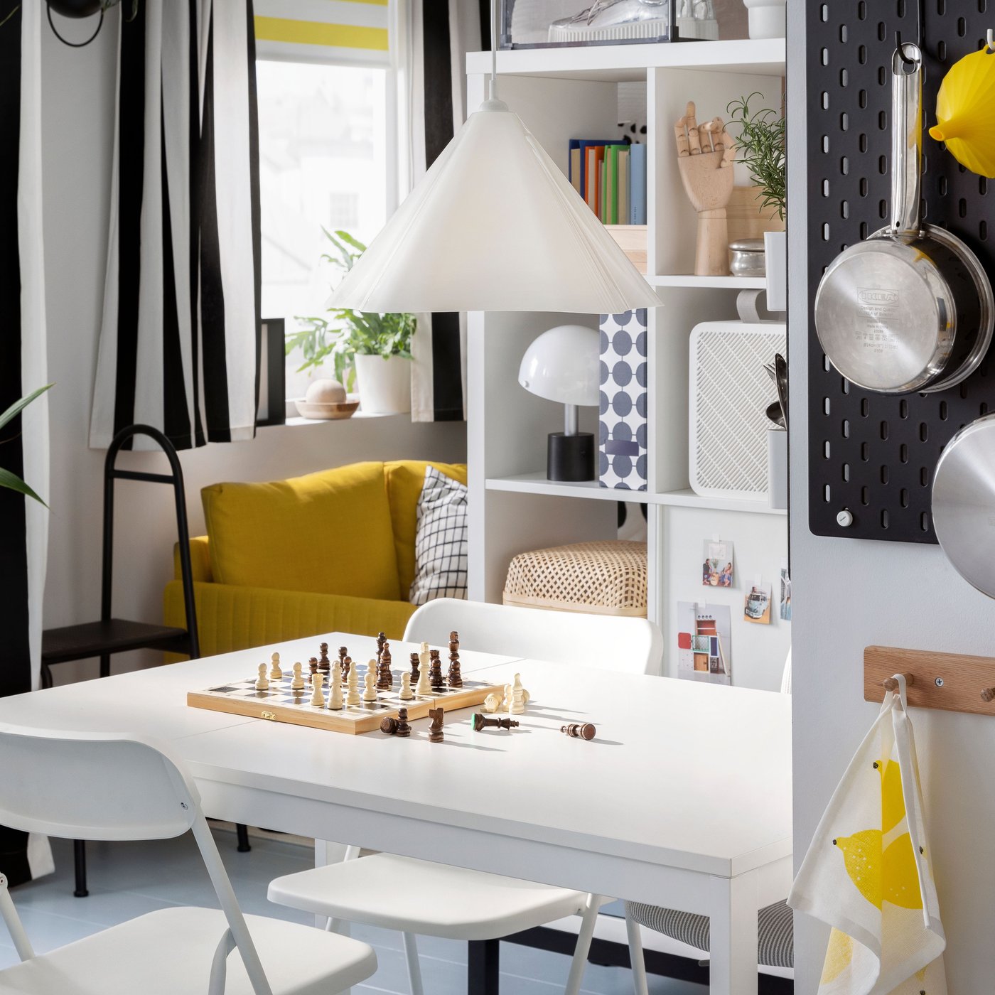 A VIHALS extendable table and VIHALS folding chairs stand in a small dining room area under a white ZEBRASÄV pendant lamp.