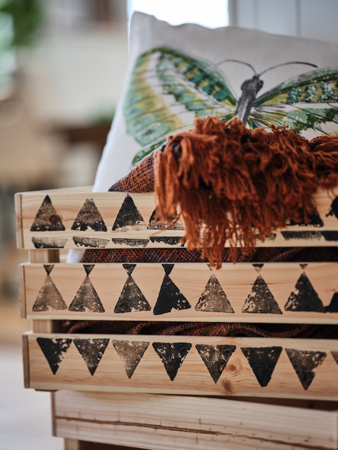 Odd textiles flowing over the top of a KNAGGLIG pine box, which in turn is decorated with a potato-stamped pattern.