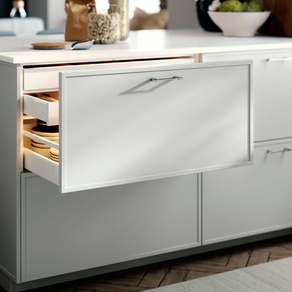 En METOD kökslåda med en ASPUDDEN lådfront i ljusgrått, öppnade, något avslöjande skålar inuti.