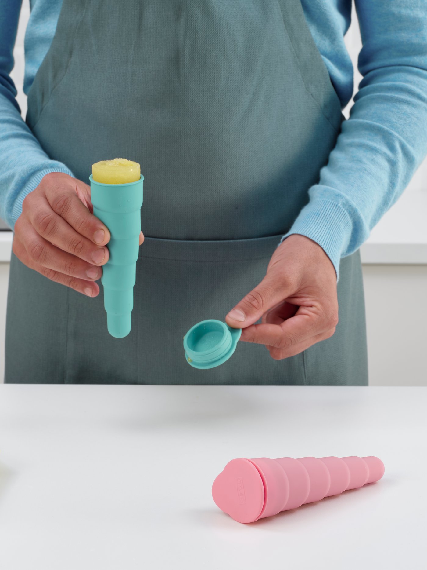 A person holding UPPFYLLD ice lolly maker filled with juice or fruit yogurt ice cream