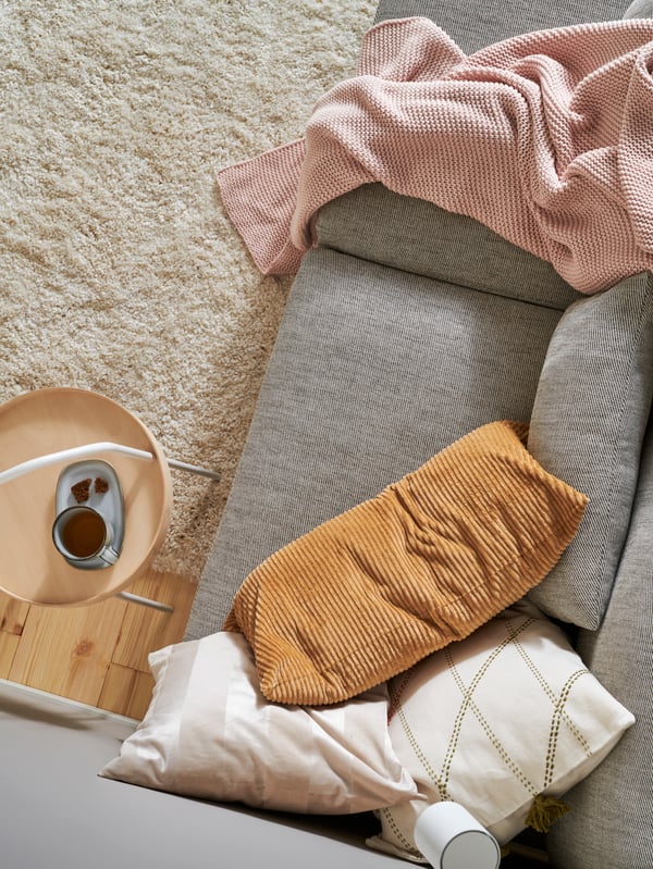 Sofa with three cushions, a white rug, a pale pink INGABRITTA throw and a BURVIK side table in white steel and birch veneer.