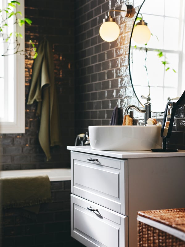 A light green VALLASÅN bath towel on a hook near a light grey GODMORGON vanity with 2 drawers below a LINDBYN mirror.