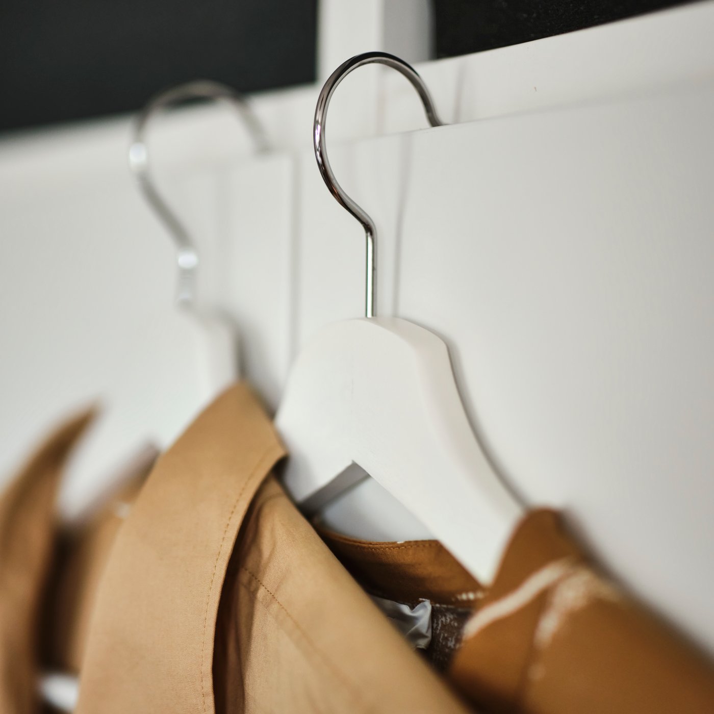 A close-up of two shirts hanging from white BUMERANG hangers.