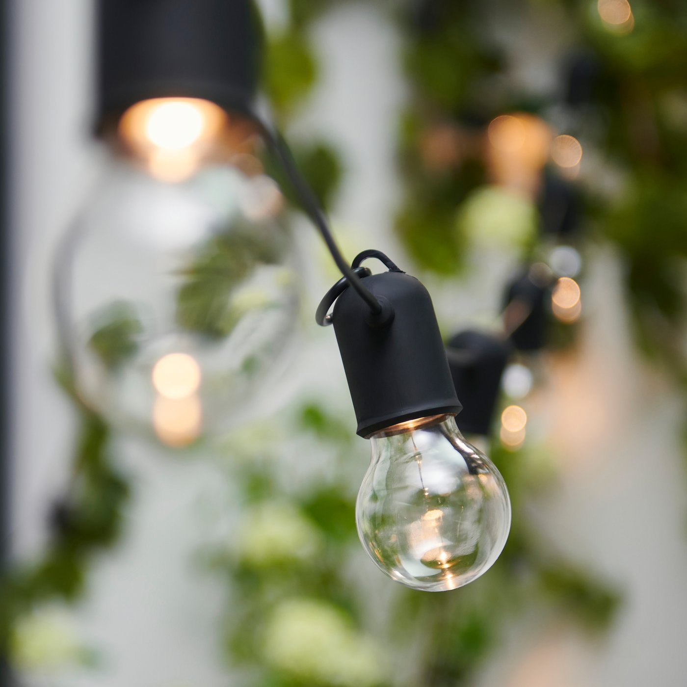 En detaljbild på en ljusslinga som hänger utomhus.