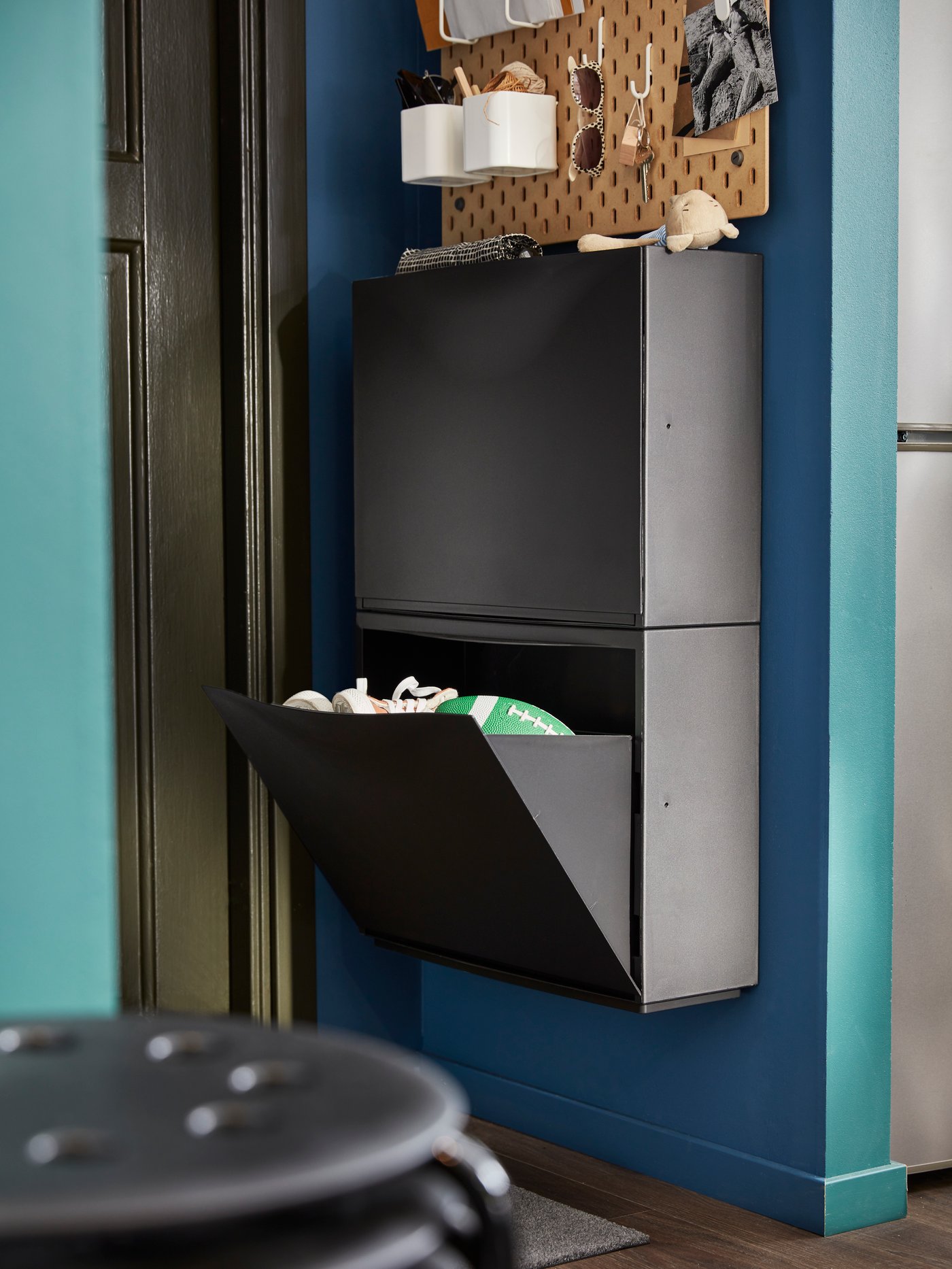 Un zapatero TRONES negro con uno de sus cajones abiertos mostrando zapatillas.