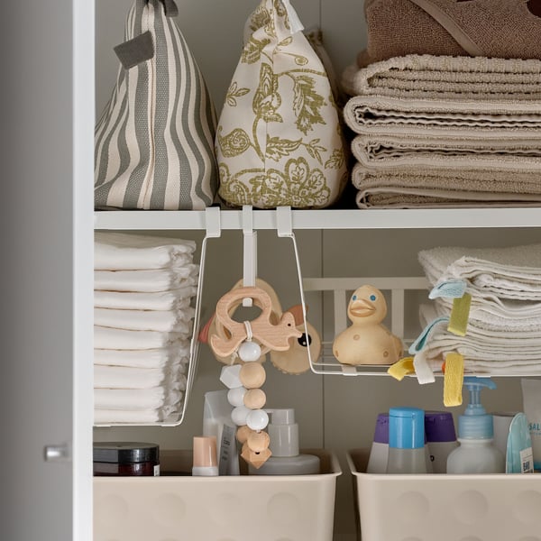 NOJIG organisers on a cabinet shelf holding fabric bags, folded towels and cleaning products alongside other stored items.