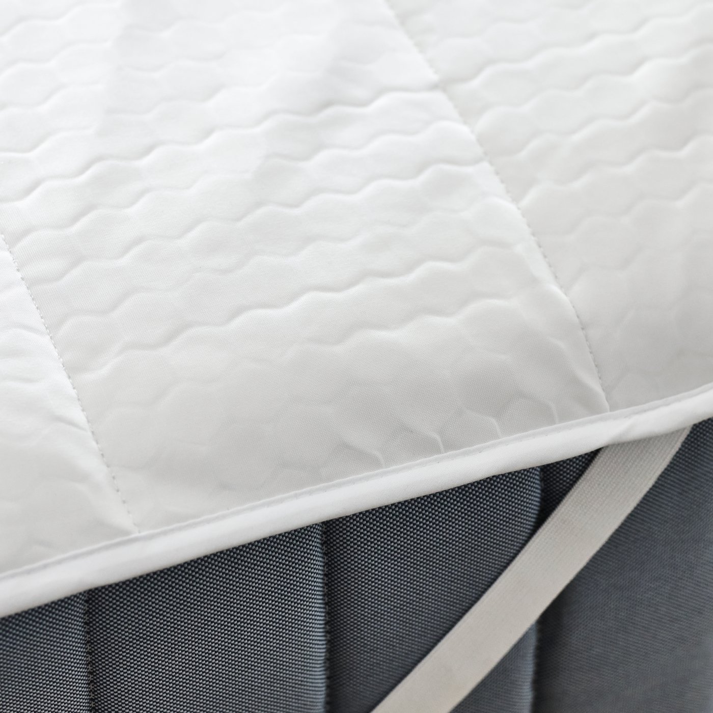 A ROSENVIAL mattress protector placed over a grey mattress.