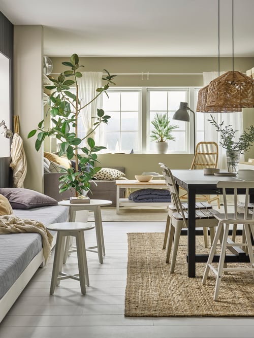 A NORDVIKEN table and some chairs are on a LOHALS rug, with pendant lamps hanging above. Next to the table are round tables.