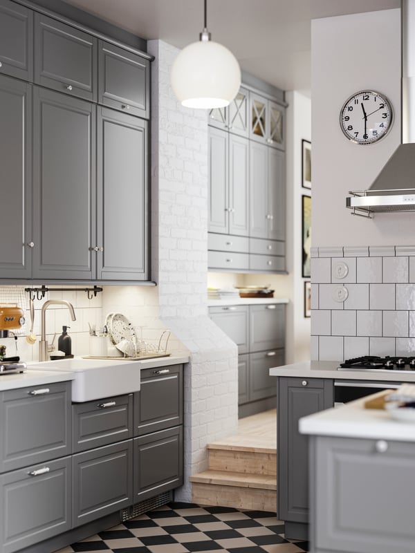A kitchen with grey BODBYN fronts and a white HAVSEN sink bowl with visible front leading into a hallway with more cabinets.