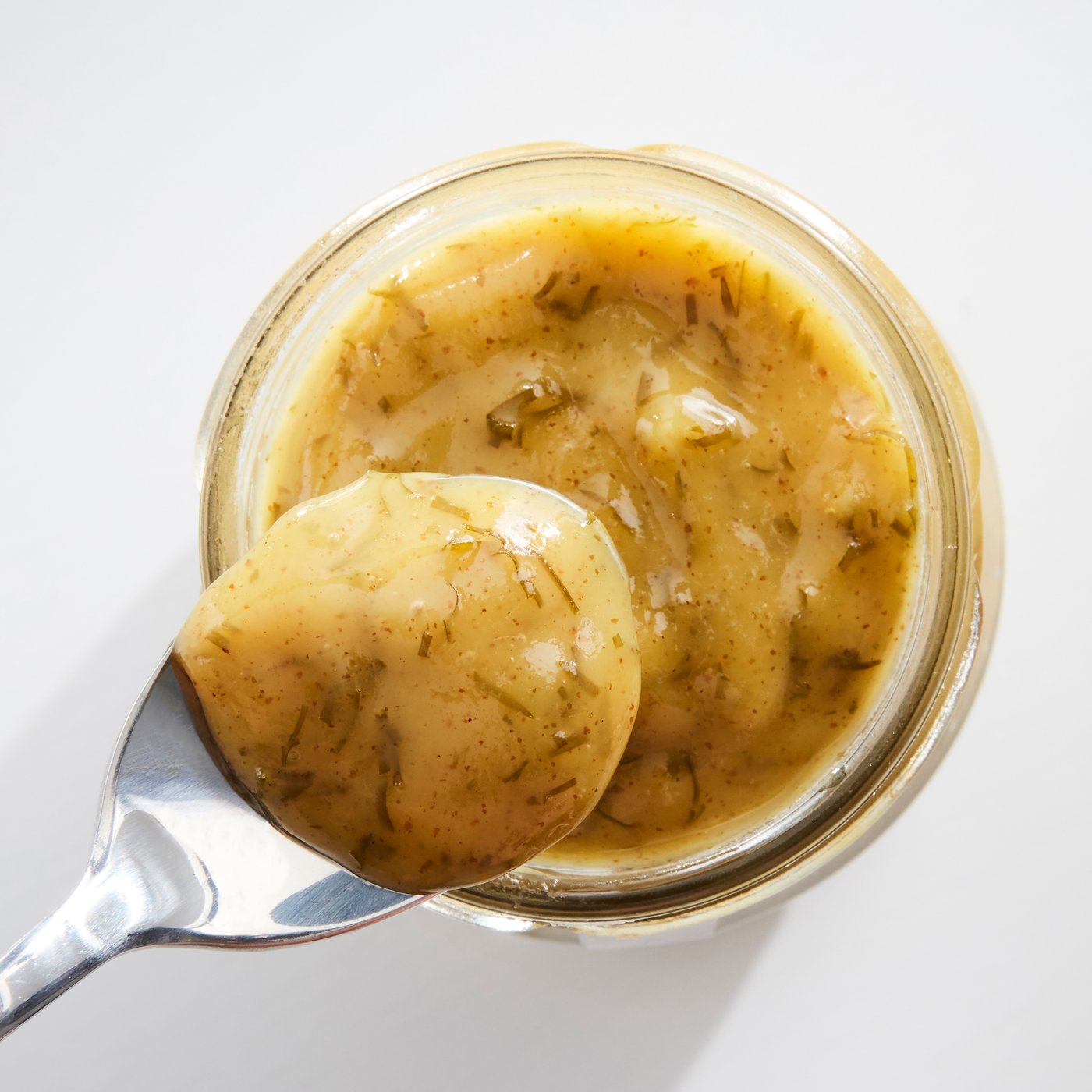 Una salsa di senape aromatica e leggermente dolce su un ciotolina di vetro e su un cucchiaio. 