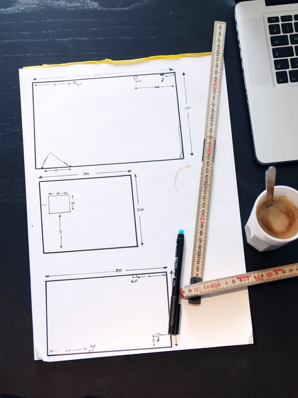 Un plan dessiné sur une feuille, avec un metré et un stylo