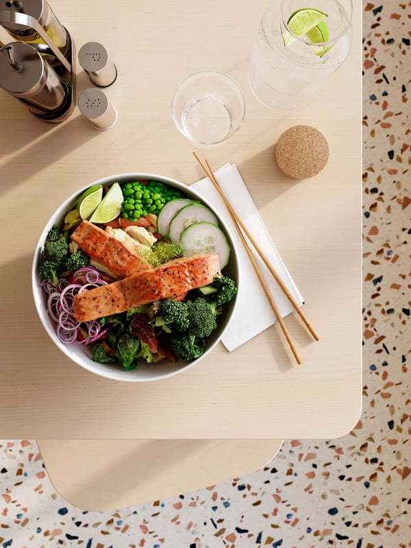 A poke-style salmon dish in a white IKEA 365+ bowl framed by TREBENT chopsticks and other tableware on a RÖNNINGE bar table.
