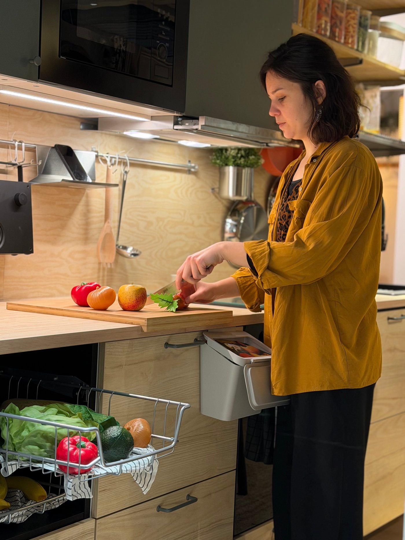 Aline de @studiogubri coupant des légumes dans sa cuisine, avec son légumier ouvert.