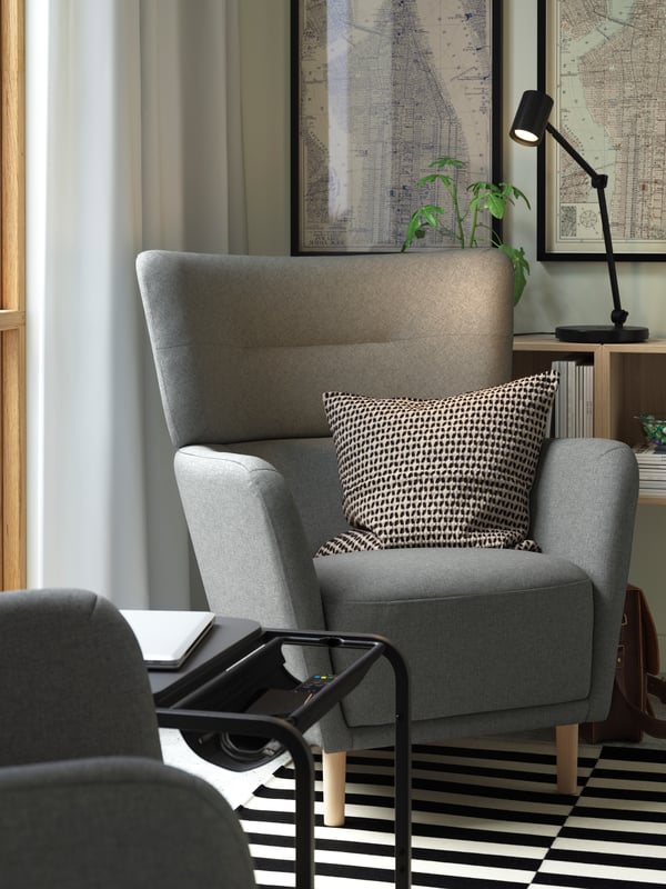 Two grey OSKARSHAMN armchairs and a small black OLSERÖD laptop table placed by a large window. Plus a cosy KUSTFLY cushion.