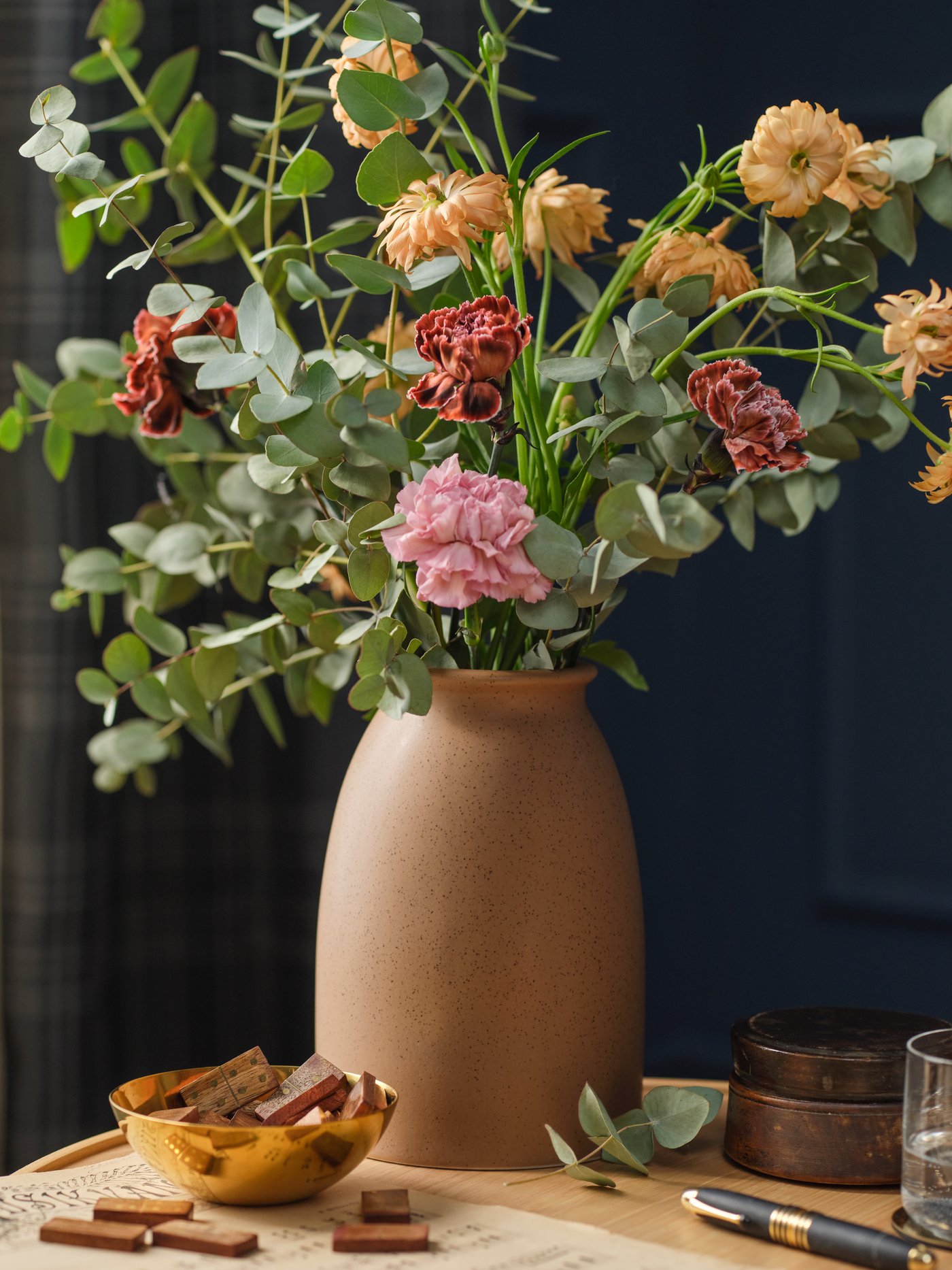 A light brown KOPPARBJÖRK vase with a SMYCKA artificial bouquet sits on a dining table.