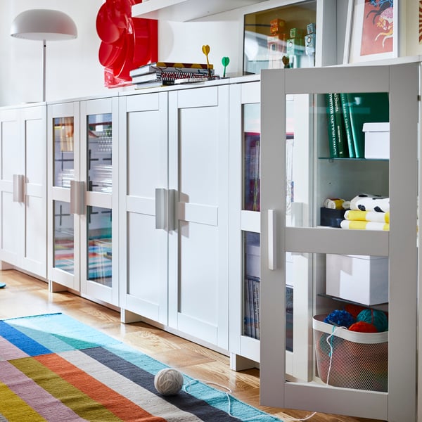 White BRIMNES storage cabinets with glass and solid doors with items neatly displayed inside.  