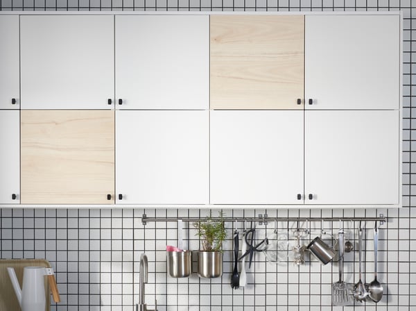 Organizador de cocina con puertas blancas y cafes, barra de cocina color metal en su inferior con elementos colgados.