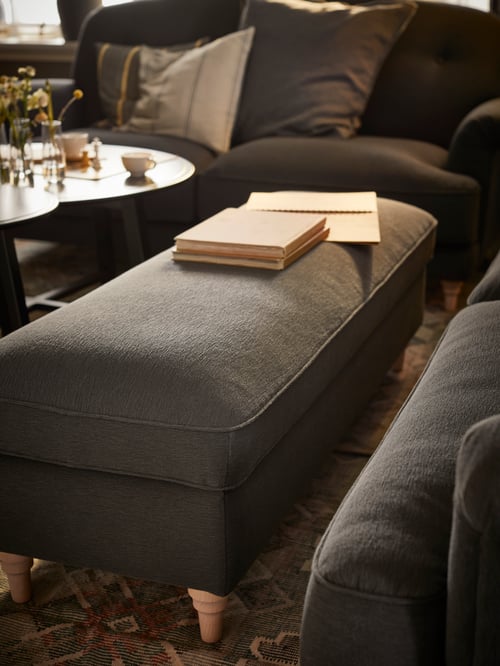 Living room area featuring a bench with storage, books, a coffee table, a standard sofa and multiple cushions.