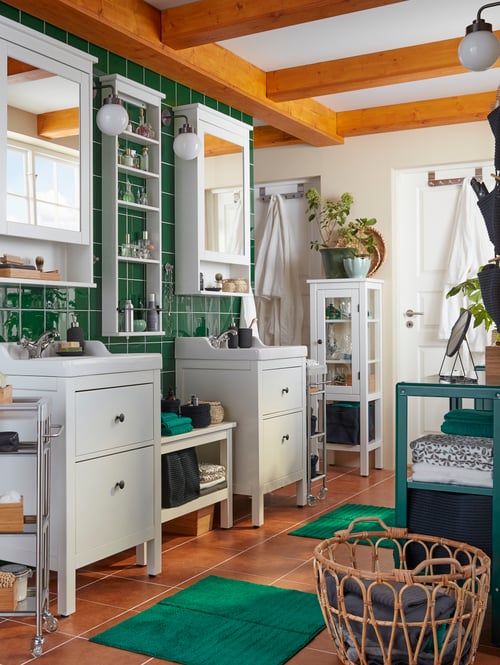 Bathroom featuring two mirror cabinets, two storage units, a bench, a high cabinet with glass doors, and a basket.