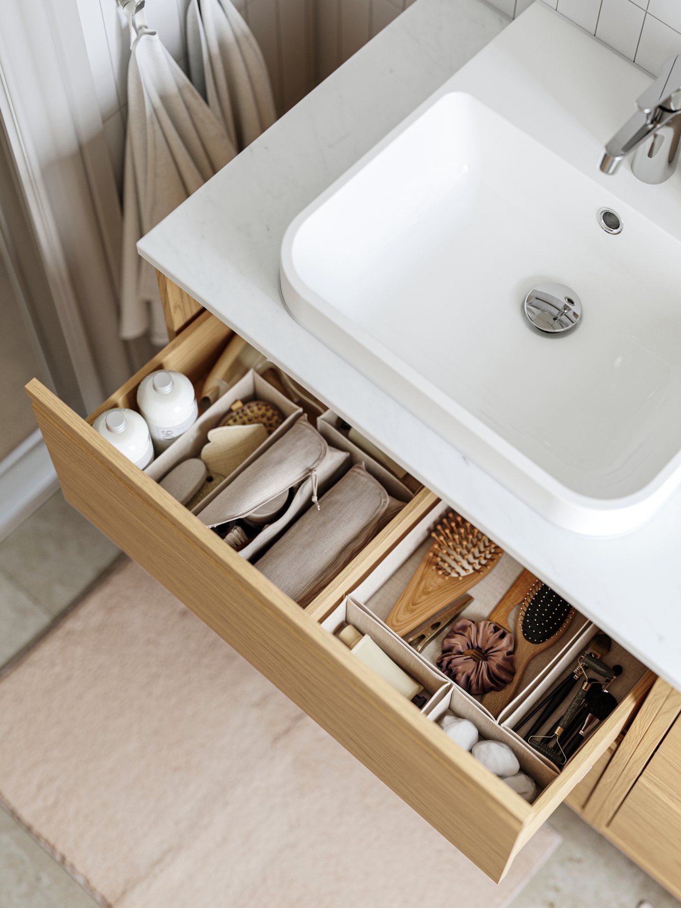 An ÄNGSJÖN wash-stand with drawers has one drawer pulled out and there are beige BOLLÖSUND drawer organisers inside.